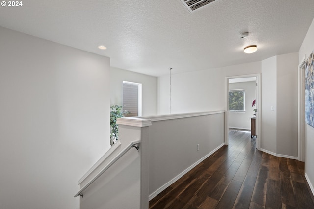 corridor with dark wood-type flooring and a textured ceiling