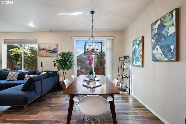 dining space with dark wood-type flooring, a healthy amount of sunlight, and a notable chandelier