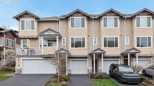 multi unit property featuring aphalt driveway, stone siding, and an attached garage