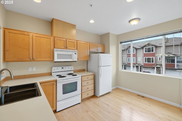 kitchen with visible vents, light countertops, light wood-style floors, white appliances, and a sink