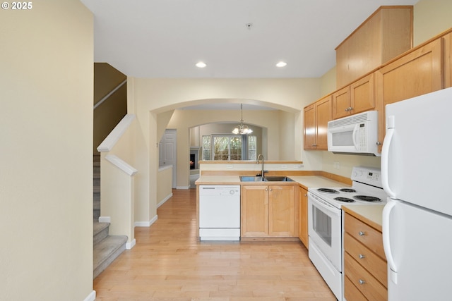 kitchen featuring white appliances, a peninsula, recessed lighting, a sink, and light wood-style floors