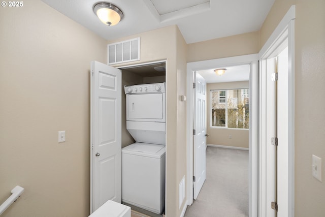 clothes washing area with visible vents, light carpet, stacked washer and dryer, baseboards, and laundry area