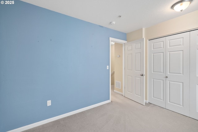 unfurnished bedroom featuring baseboards, visible vents, light carpet, and a closet