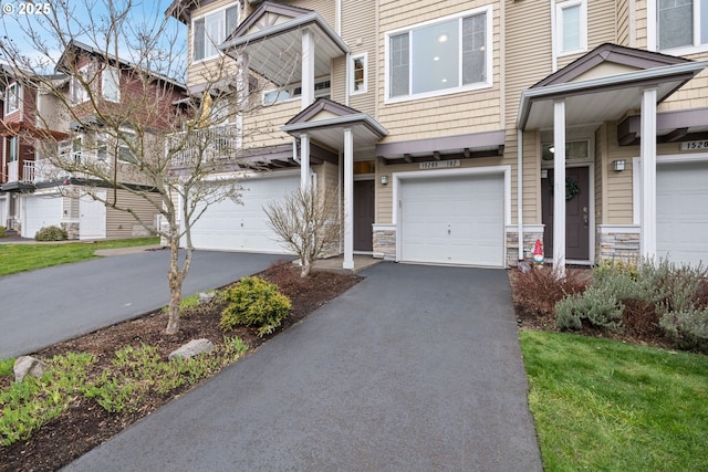 townhome / multi-family property with stone siding, a garage, and driveway