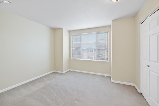 unfurnished bedroom with a closet, baseboards, carpet, and visible vents