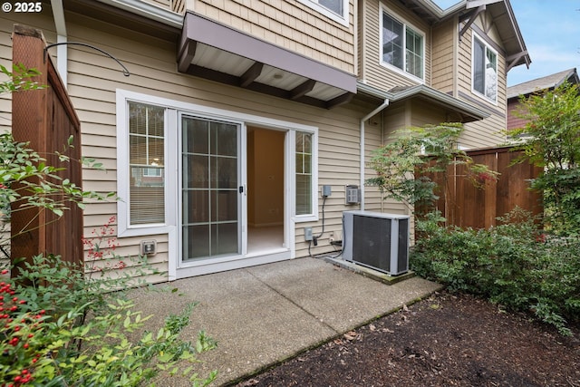 doorway to property with a patio, central AC unit, and fence