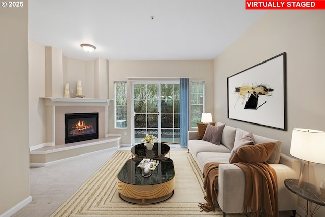 living room with a tile fireplace, baseboards, and carpet floors