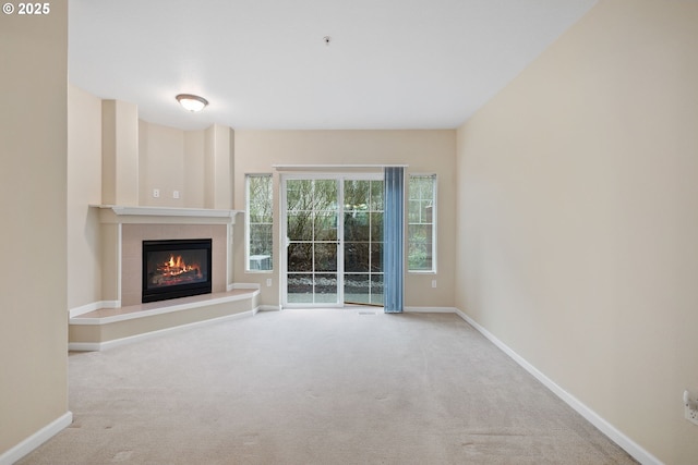 unfurnished living room with carpet flooring, a fireplace, and baseboards