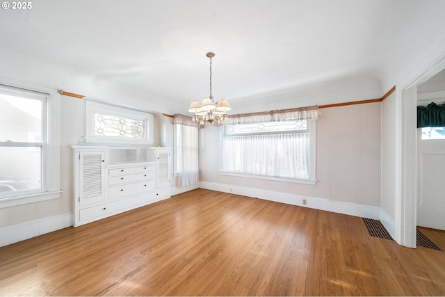 unfurnished dining area featuring a chandelier, light hardwood / wood-style flooring, and a wealth of natural light