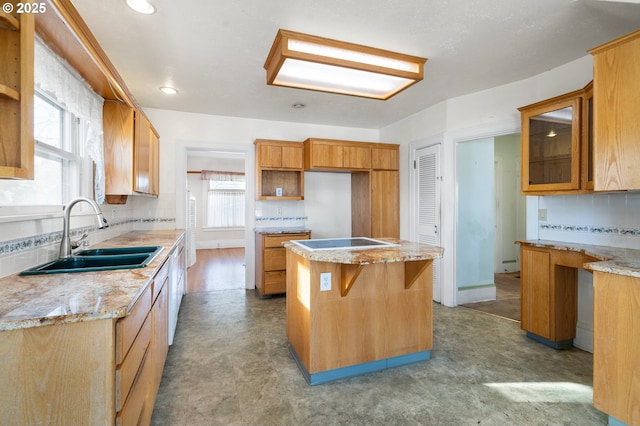 kitchen featuring sink, light stone counters, black electric cooktop, a kitchen island, and backsplash