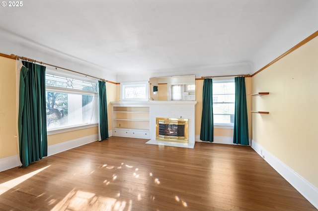 unfurnished living room with plenty of natural light, a fireplace, and wood-type flooring