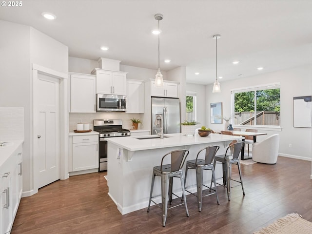 11179 SE Honorable Way, Happy Valley, OR 97086 - kitchen featuring stainless steel appliances, dark wood finished floors, a kitchen breakfast bar, a kitchen island with sink, and white cabinets