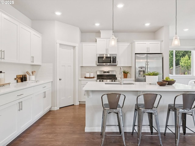 11179 SE Honorable Way, Happy Valley, OR 97086 - kitchen featuring appliances with stainless steel finishes, tasteful backsplash, white cabinets, a kitchen breakfast bar, and recessed lighting
