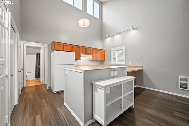 kitchen with a high ceiling, heating unit, white fridge, and dark hardwood / wood-style flooring