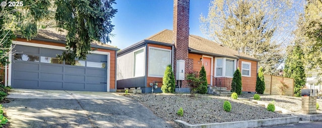 view of front of home featuring concrete driveway, a chimney, and a garage