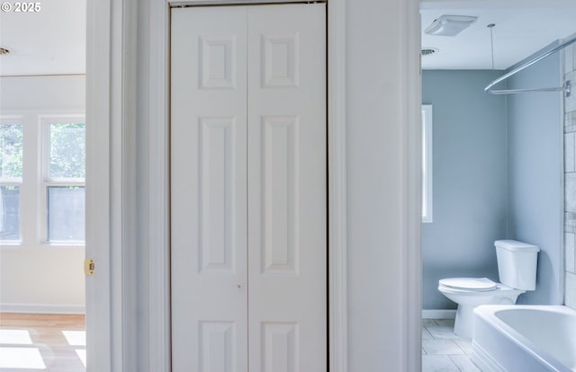 full bathroom featuring baseboards, a closet, toilet, and a bathtub