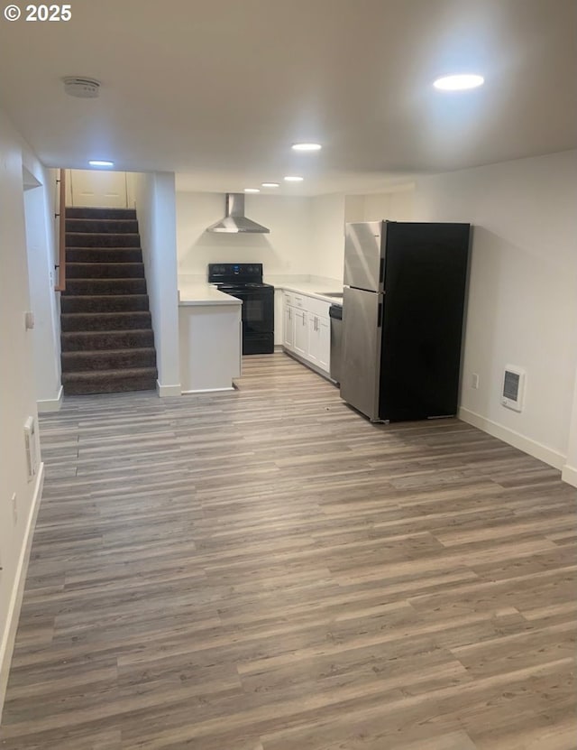 interior space with baseboards, white cabinetry, wall chimney range hood, and stainless steel appliances