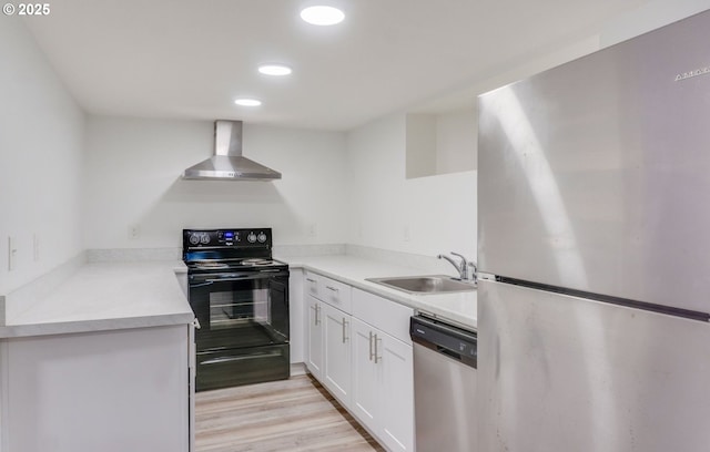 kitchen with white cabinetry, a sink, stainless steel appliances, recessed lighting, and wall chimney exhaust hood