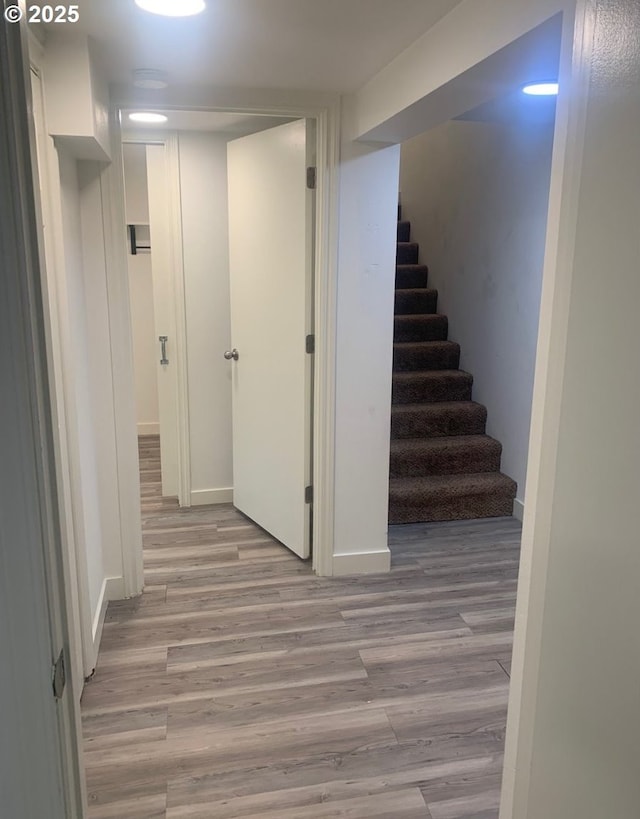 finished below grade area with light wood-style floors, baseboards, and stairway