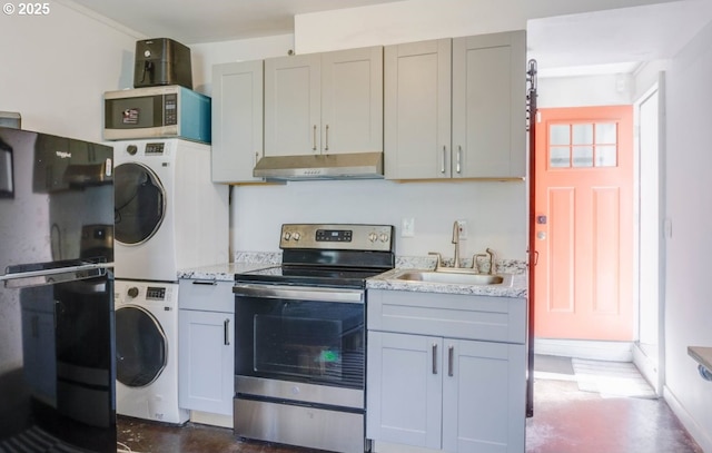 kitchen featuring gray cabinets, under cabinet range hood, a sink, stacked washer / drying machine, and stainless steel appliances