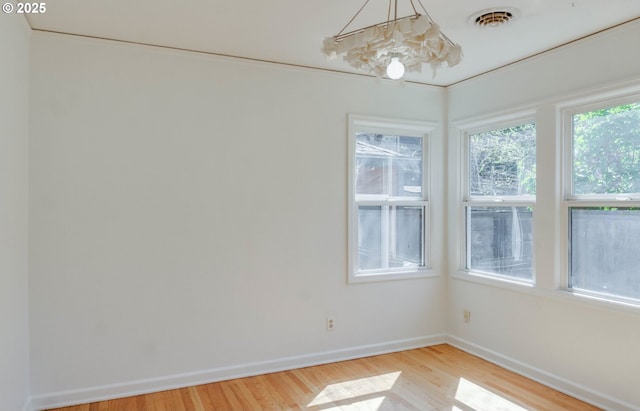 empty room with baseboards, light wood finished floors, and visible vents