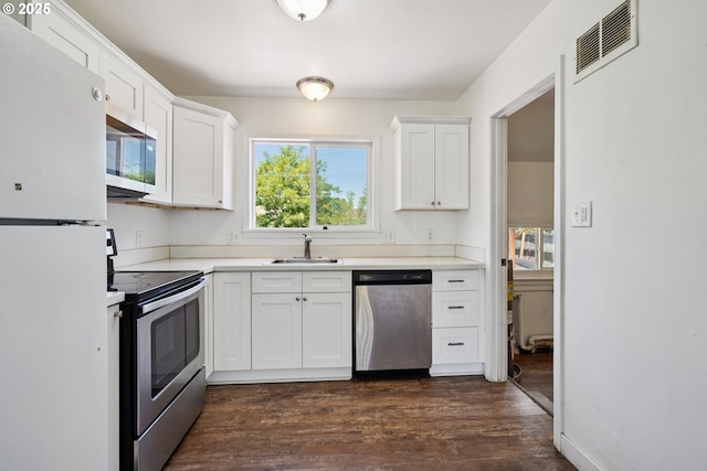 1059 16th Ave SW, Albany, OR 97321 - kitchen featuring appliances with stainless steel finishes, a sink, dark wood-style flooring, and white cabinetry