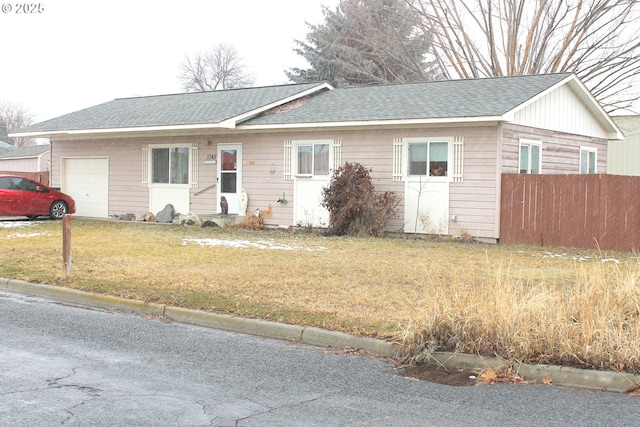 single story home featuring a garage, fence, a front lawn, and roof with shingles