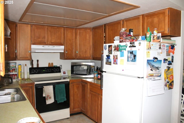 kitchen featuring electric range, stainless steel microwave, freestanding refrigerator, light countertops, and under cabinet range hood