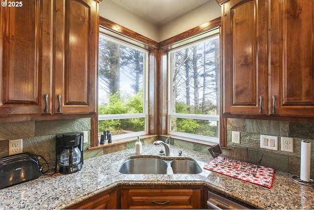 kitchen with a sink, tasteful backsplash, and light stone countertops