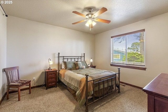 bedroom featuring light carpet, baseboards, a ceiling fan, and a textured ceiling