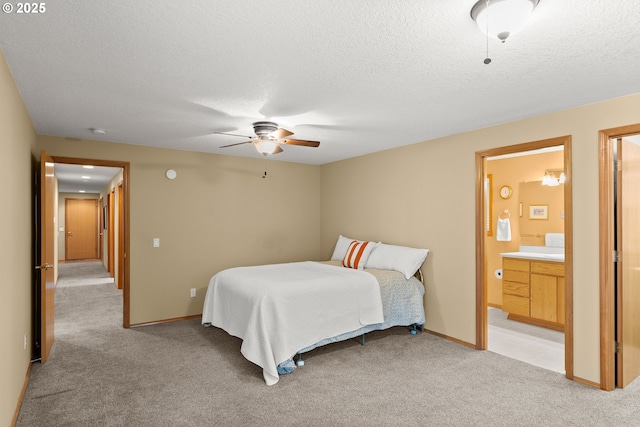 bedroom with ceiling fan, light colored carpet, a textured ceiling, and ensuite bath