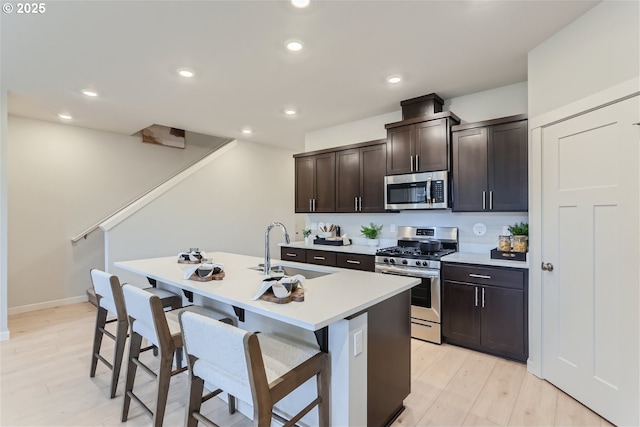 5990 Henshaw St SE, Albany, OR 97322 - kitchen with appliances with stainless steel finishes, a kitchen breakfast bar, an island with sink, light countertops, and light wood-type flooring