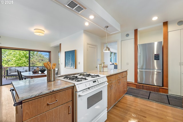 2687 NW Cornell Rd, Portland, OR 97210 - kitchen with stainless steel fridge, gas range gas stove, light wood-style floors, light stone counters, and pendant lighting