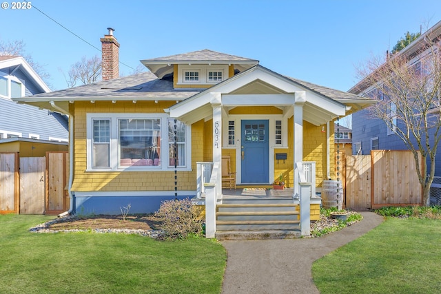 bungalow-style home with a chimney, fence, and a front yard