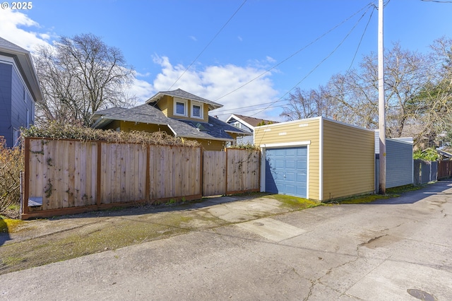 detached garage featuring driveway and fence