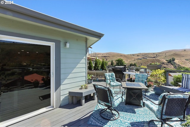 wooden deck with an outdoor fire pit, outdoor dining area, and a mountain view