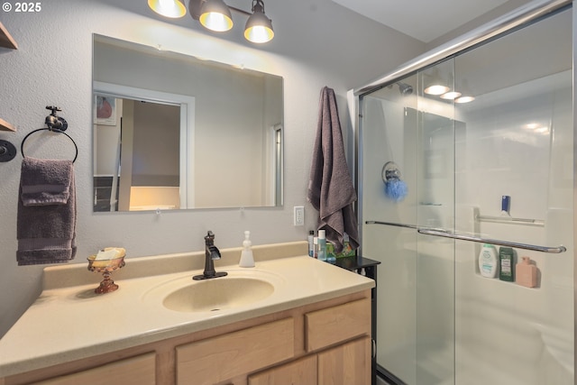 bathroom featuring a textured wall, a shower stall, and vanity