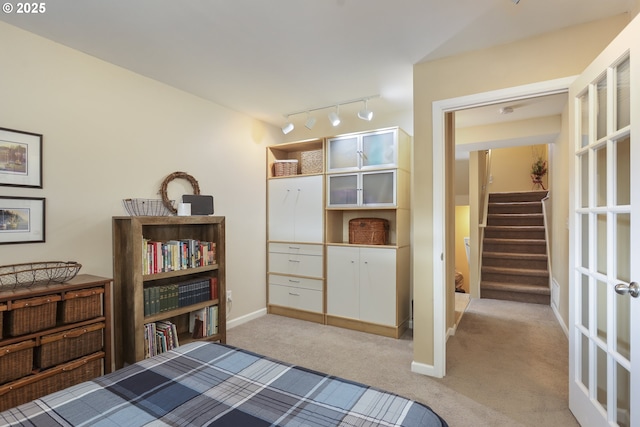 bedroom featuring rail lighting, baseboards, and light colored carpet