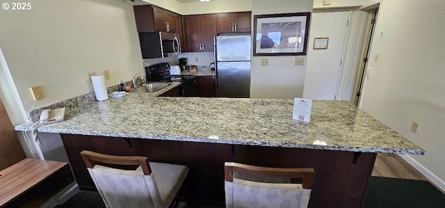 kitchen featuring a breakfast bar, kitchen peninsula, and appliances with stainless steel finishes