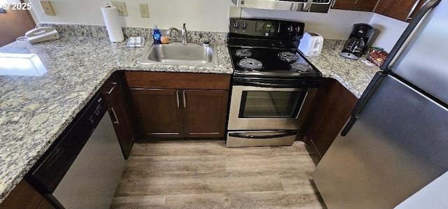 kitchen with sink, dark brown cabinets, light wood-type flooring, stainless steel appliances, and light stone countertops