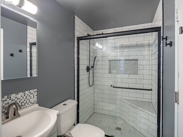 bathroom featuring a shower with door, vanity, decorative backsplash, and toilet