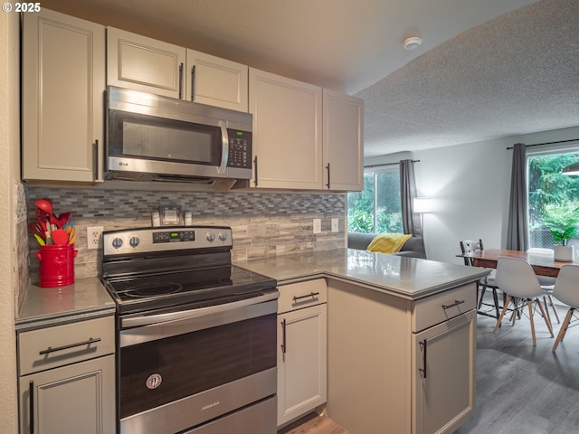 kitchen featuring stainless steel appliances, white cabinetry, tasteful backsplash, and kitchen peninsula