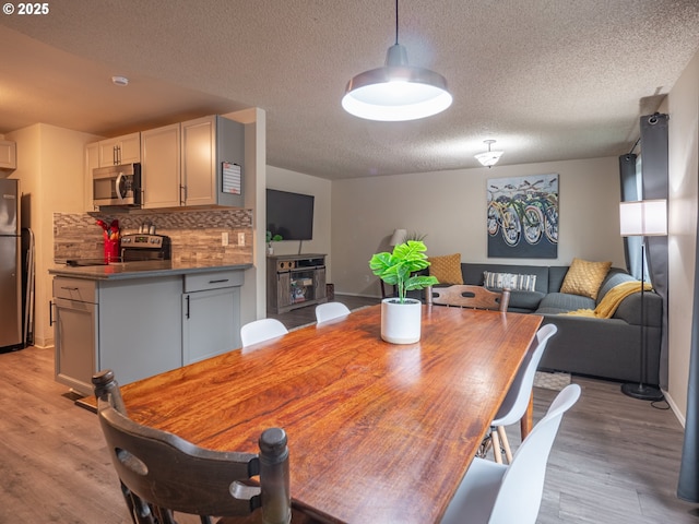 dining area with a textured ceiling and light wood-type flooring