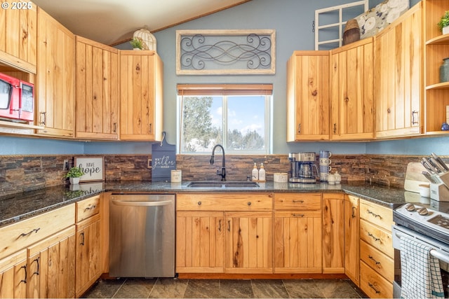 kitchen with lofted ceiling, appliances with stainless steel finishes, sink, and dark stone counters