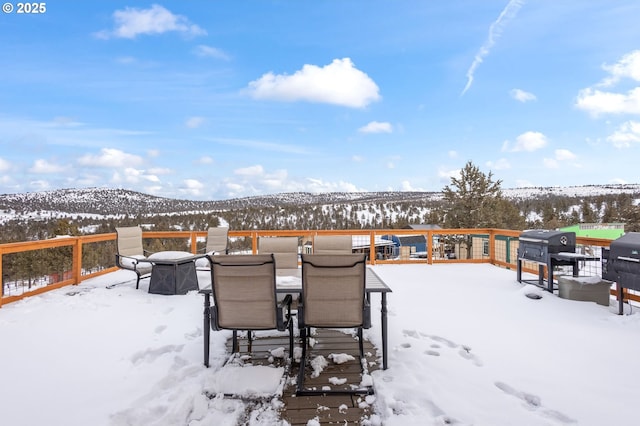 snow covered deck with a mountain view and grilling area