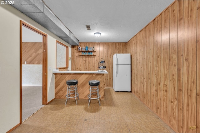 61241 Perry Creek Rd, Saint Helens, OR 97051 - bar with tile patterned floors, a textured ceiling, freestanding refrigerator, a bar, and wood walls