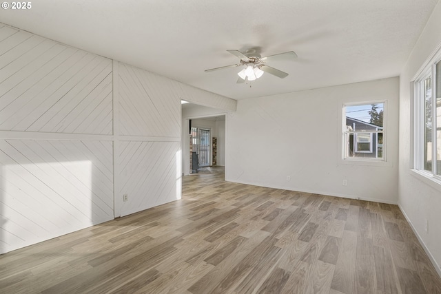 unfurnished room with light wood finished floors, ceiling fan, and baseboards