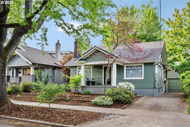 bungalow featuring a porch, driveway, and a chimney