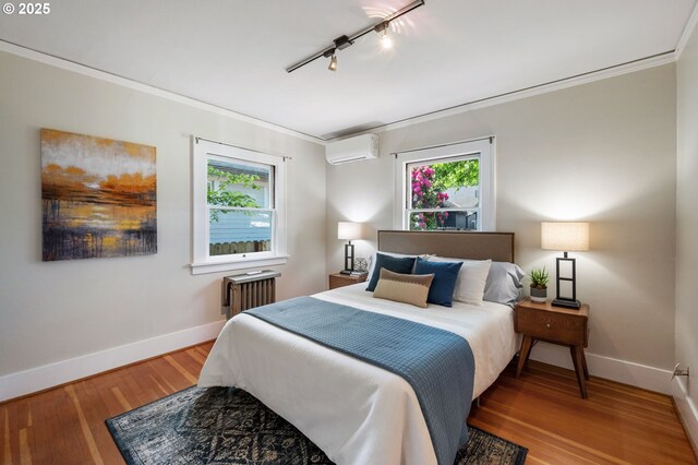 bedroom with track lighting, a wall mounted air conditioner, baseboards, and crown molding
