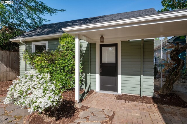entrance to property with fence and roof with shingles